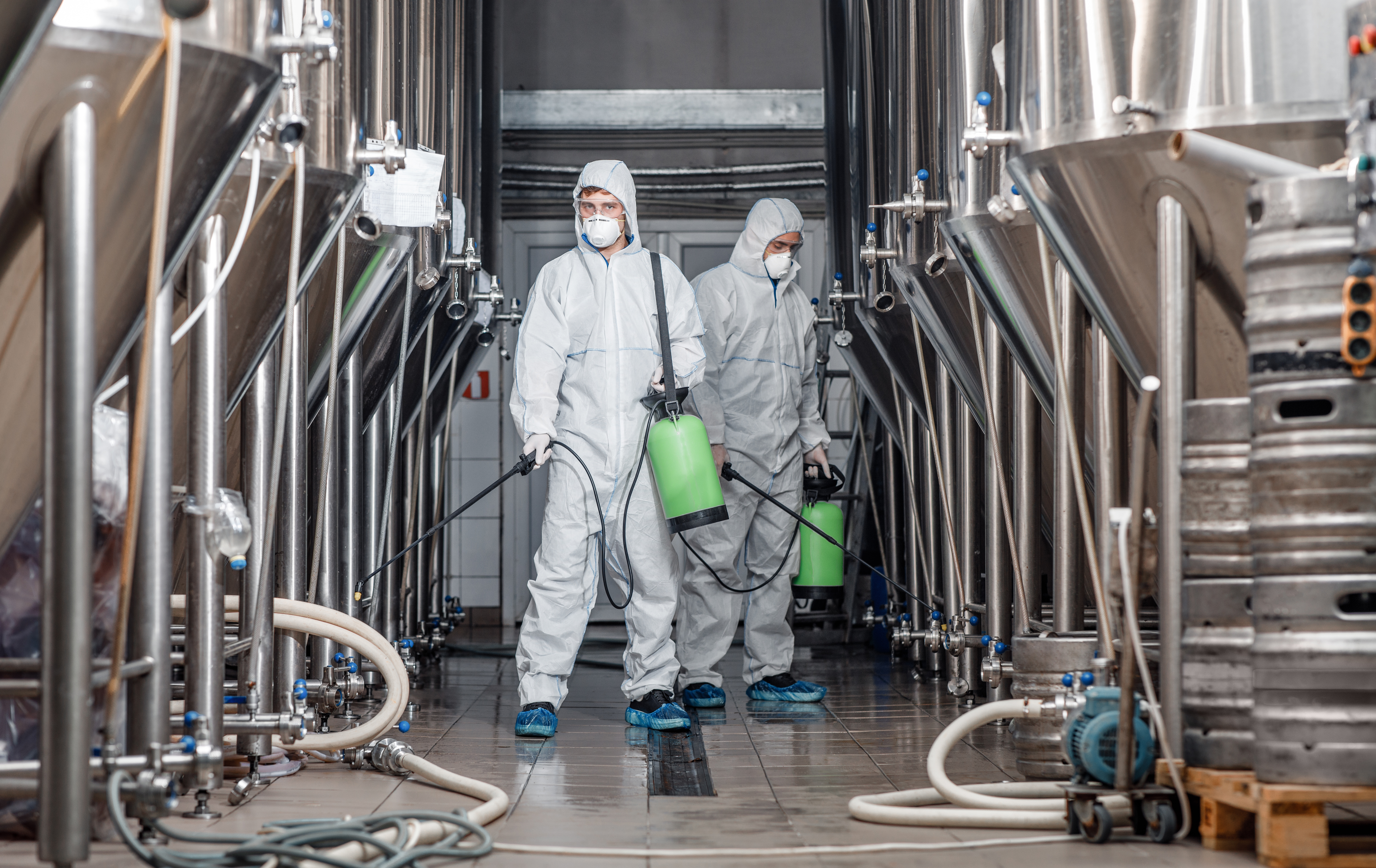 Quarantine and prevention on factory. Man in protective suit and mask disinfects beer plant, panorama, free space